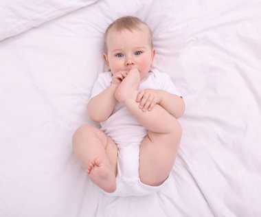 Evdeki yatakta uzanmış şirin küçük bebek, üst manzara.