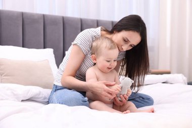Anne, tatlı küçük bebeği ve evde yatağında oyuncağıyla