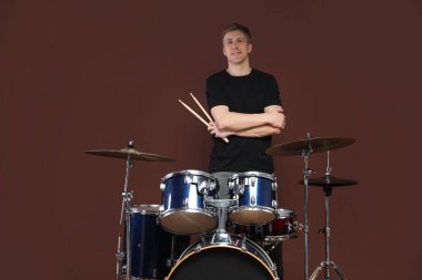 Kahverengi arka planda davul setiyle gülümseyen adam.