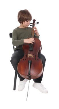 Küçük çocuk beyaz arka planda sandalyede keman çalıyor.