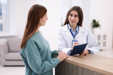 Klinikteki resepsiyonda hastaya yardım eden tıbbi asistan