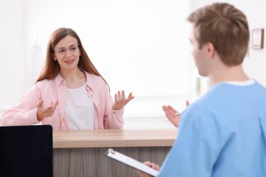 Klinikteki resepsiyonda hastaya yardım eden tıbbi asistan