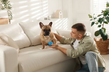 Evdeki kanepenin yanında sevimli köpeği ve oyuncağıyla genç bir adam.
