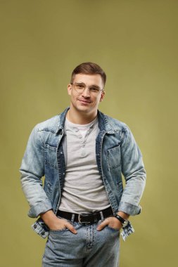 Moda modeli. Yeşil arka planda gözlüklü ve ceketli yakışıklı bir adam.