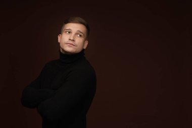 Moda modeli. Koyu kahverengi arkaplana karşı poz veren yakışıklı adam, metin için boşluk