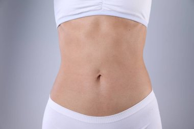 Kilo verdikten sonra gri arka planda iç çamaşırlı kadın, yakın plan.