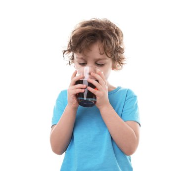 Küçük çocuk beyaz arka planda taze nar suyu içiyor.