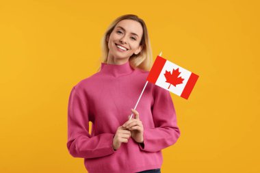 Turuncu arka planda Kanada bayrağı olan mutlu kadın.