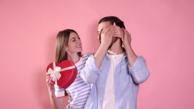 Romantik bir randevu. Pembe arka planda erkek arkadaşına sürpriz yapan bir kadın.