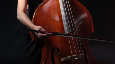 Siyah arka planda çift bas çalan kadın, yakın plan.