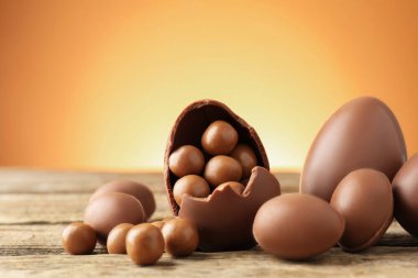 Ahşap masadaki çikolatalı yumurtalar, renkli arka plana karşı, yakın plan. Mutlu Paskalyalar
