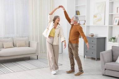 Mutlu yaşlı çift evde dans ediyor.