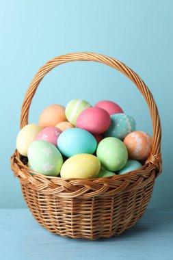 Masadaki sepetteki güzel Paskalya yumurtaları açık mavi arka planda