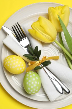 Paskalya kutlaması. Lale çiçekleri ve sarı arka planda boyanmış yumurtalar, üst manzara.