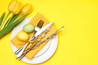 Paskalya kutlaması. Lale çiçekleri, boyalı yumurtalar ve sarı arka planda söğüt dalları olan şenlik masası düzlüğü. Metin için boşluk
