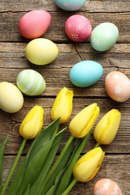 Boyanmış Paskalya yumurtaları ve ahşap masada güzel laleler.