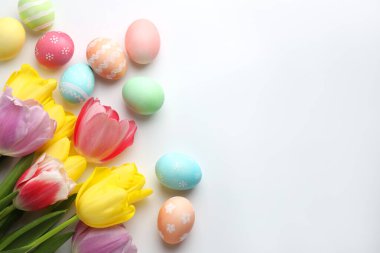 Boyalı Paskalya yumurtaları ve beyaz arka planda güzel laleler. Metin için boşluk