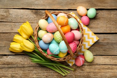 Tahta masanın üzerinde boyanmış yumurtalar ve laleler olan Paskalya sepeti, düz yatıyordu.