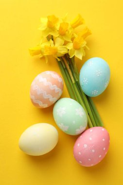 Boyanmış Paskalya yumurtaları ve turuncu arka planda güzel nergisler.