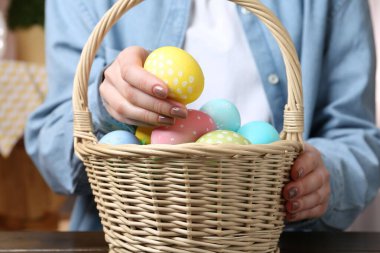 Paskalya sepetinde boyanmış yumurtalı bir kadın, kapalı masa, yakın plan.