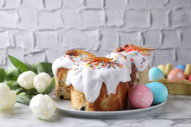 Lezzetli Paskalya pastaları, laleler ve beyaz mermer masaya boyanmış yumurtalar, yakın plan.