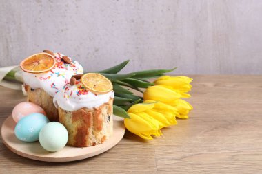 Lezzetli Paskalya pastaları, laleler ve boyanmış yumurtalar gri arka planda. Metin için boşluk