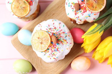 Lezzetli Paskalya pastaları, laleler ve pembe masanın üzerine boyanmış yumurtalar.