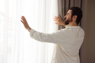 Evde şık pencere perdeleri açan adam