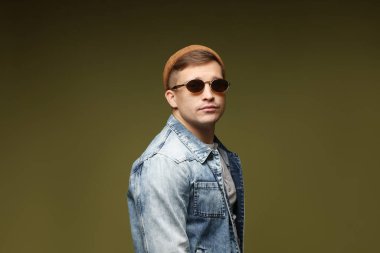 Moda modeli. Şapkalı, güneş gözlüklü ve ceketli yakışıklı bir adam.