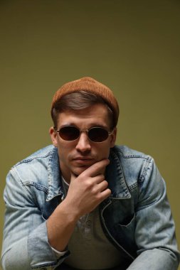 Moda modeli. Şapkalı, güneş gözlüklü ve ceketli yakışıklı bir adam.