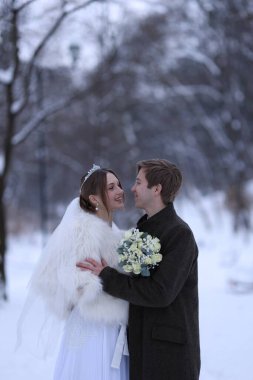 Mutlu yeni evli çift, bir buket çiçekle kış günü açık havada, mesaj atmak için yer var.