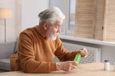 Hafıza kaybı. Hapları olan yaşlı bir adam içeride tahta masada bir şeyler hatırlamaya çalışıyor.