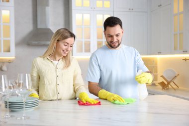 Mutfakta beyaz mermer masayı temizleyen çift.