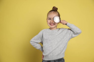 Sarı zemin üzerinde büyüteç olan küçük kız, mesaj için boşluk