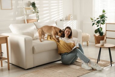 Evdeki kanepenin yanında tatlı köpeği olan bir kadın.