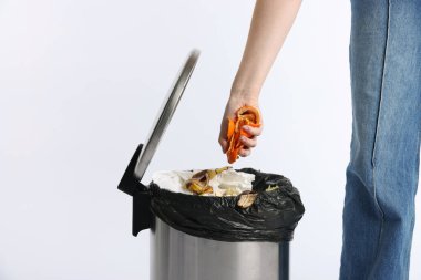 Mandalina kabuklarını beyaz arka planda çöpe atan kadın, yakın plan.