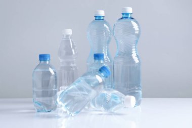 Beyaz masada gri arka planda farklı boyutlarda su şişeleri