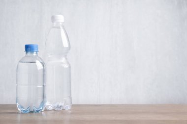 Su şişeleri ahşap masa üzerinde açık gri arkaplan, metin için boşluk