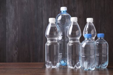 Ahşap masada farklı boyutlarda su şişeleri, metin için yer