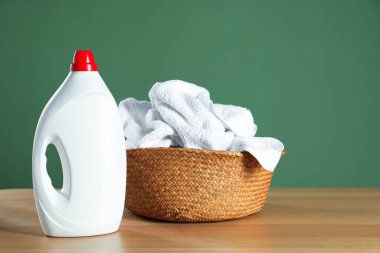 Ahşap masa üzerinde havlular ve deterjan olan çamaşır sepeti koyu yeşil arka plan, metin için boşluk