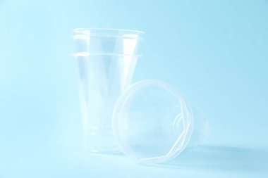Plastik ambalaj. Açık mavi arkaplanda şeffaf bardaklar, yakın plan