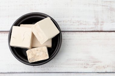 Tabaktaki taze maya parçaları açık ahşap masa, üst manzara. Metin için boşluk