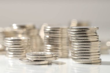 Işık arkaplanına istiflenmiş birçok bozuk para, yakın plan