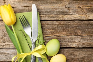 Paskalya sofrası. Lale ve ahşap arka planda boyanmış yumurtaları olan güzel gümüş takımlar, üst manzara. Metin için boşluk