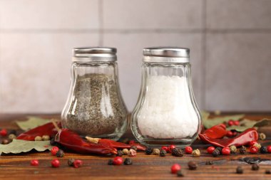 Ahşap masada baharatlı tuzluk ve biberlikler, yakın plan.