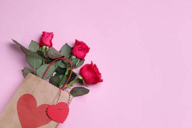 Pembe arka planda güller olan kağıt torba, üst manzara. Metin için boşluk