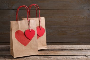 Tahta masada üzerinde kalp izleri olan kağıt torbalar. Metin için boşluk