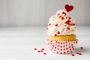 Sevgililer Günün kutlu olsun. Gri duvarın yanındaki beyaz ahşap masada kalp şeklinde serpiştirilmiş lezzetli kek, yakın plan. Metin için boşluk