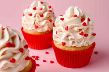 Sevgililer Günün kutlu olsun. Pembe arka planda kırmızı kalpleri olan lezzetli kekler, yakın plan.