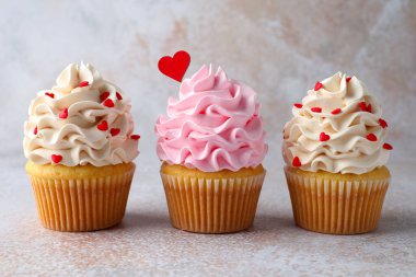 Sevgililer Günün kutlu olsun. Gri masada kırmızı kalpli lezzetli kekler, yakın plan.